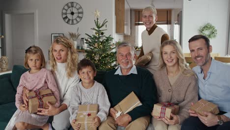 porträt einer eleganten kaukasischen familie mit weihnachtsgeschenken und blick in die kamera.