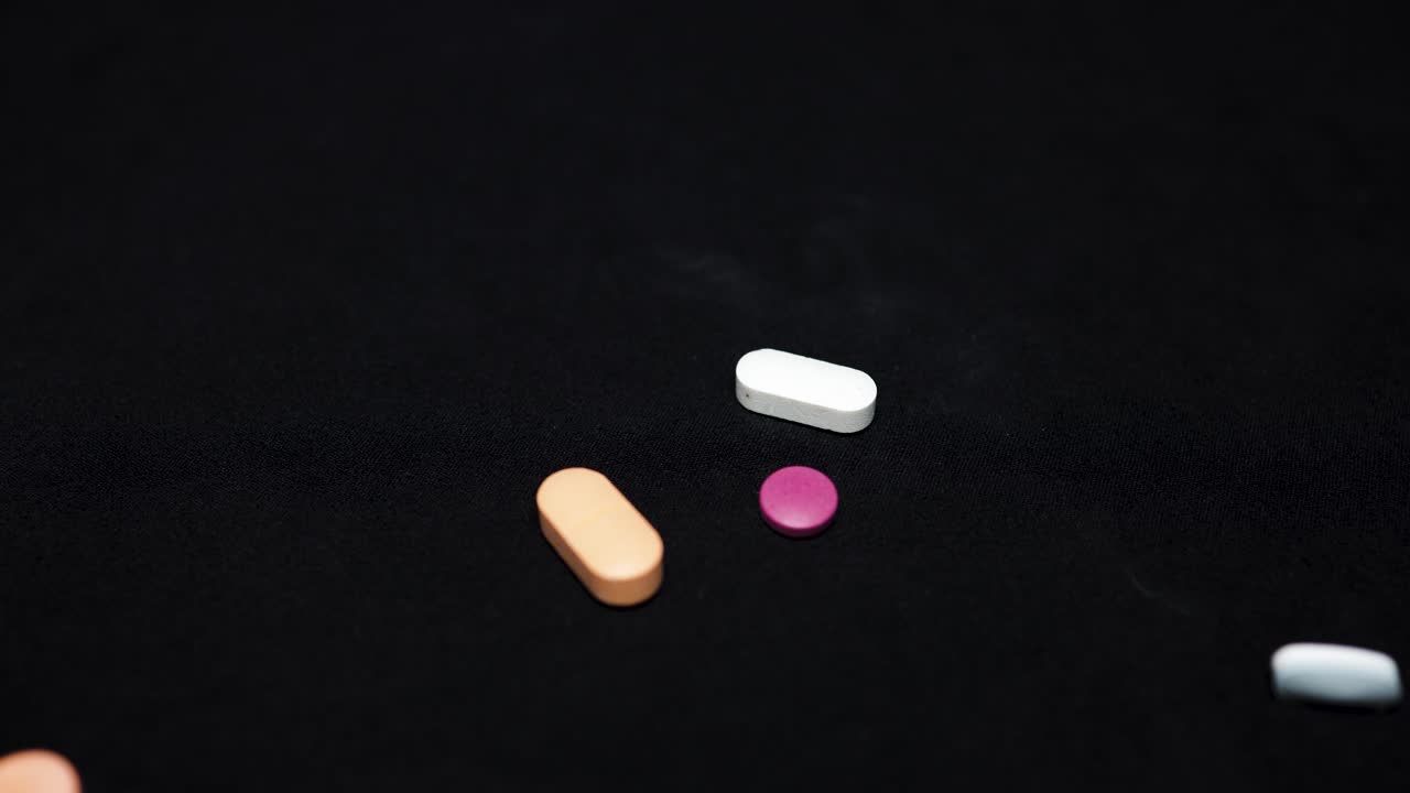 medicine tablets falling at black background at indoor lighting