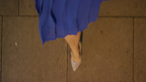 woman walking on sidewalk wearing elegant evening party dress stylish glitter shoes strolling in urban city nightlife