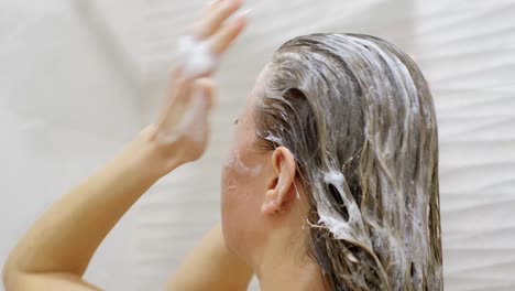 blonde girl washes her hair. white foam from shampoo on long hair. head hair care