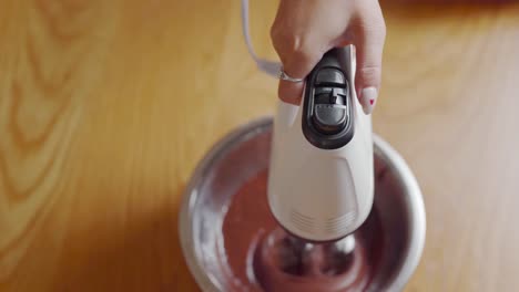 closeup-of-hand-whisking-cake-batter-in-stainless-bowl