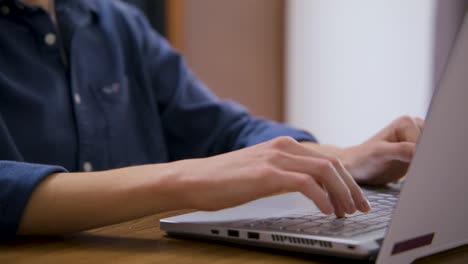 guy typing on a laptop seen from the back right side of the computer