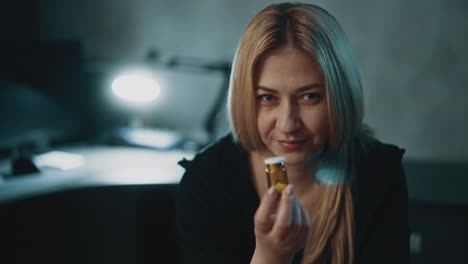 Woman-with-inscrutable-smile-holds-small-pill-bottle-in-room