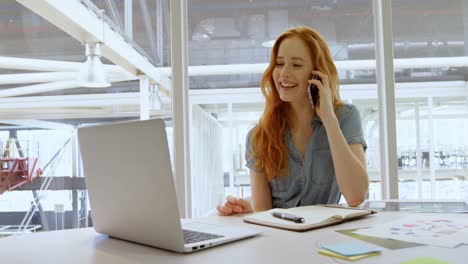 Executive-talking-on-mobile-phone-while-using-laptop-4k