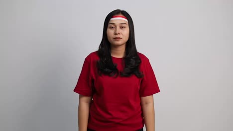excited asian young woman with red white ribbon. good news in indonesia independence day