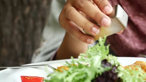 una persona está salando su comida con un batidor de sal.