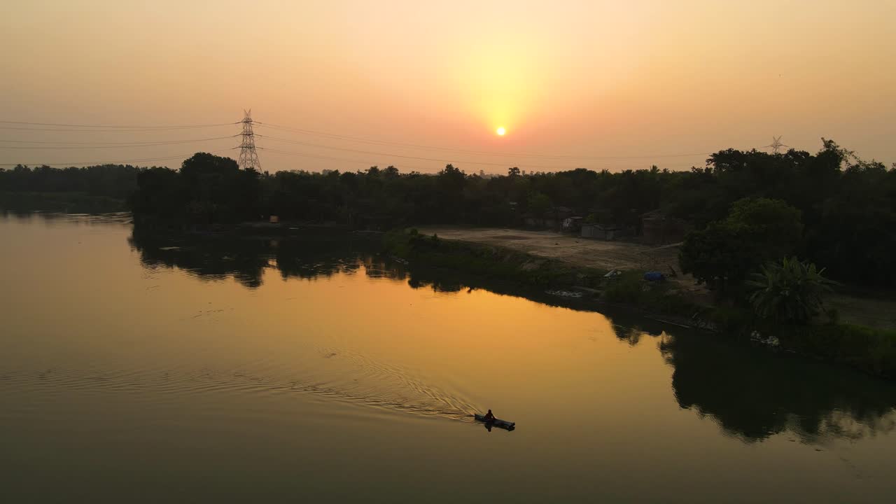 tomada de un avión no tripulado de un paisaje boscoso al amanecer, con el río brillando en la luz temprana.