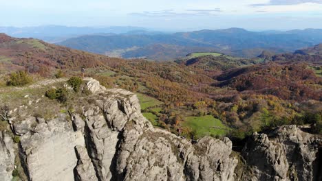 Aerial:-two-hikers-walking-along-a-very-narrow-mountain-crest-in-autumn-season