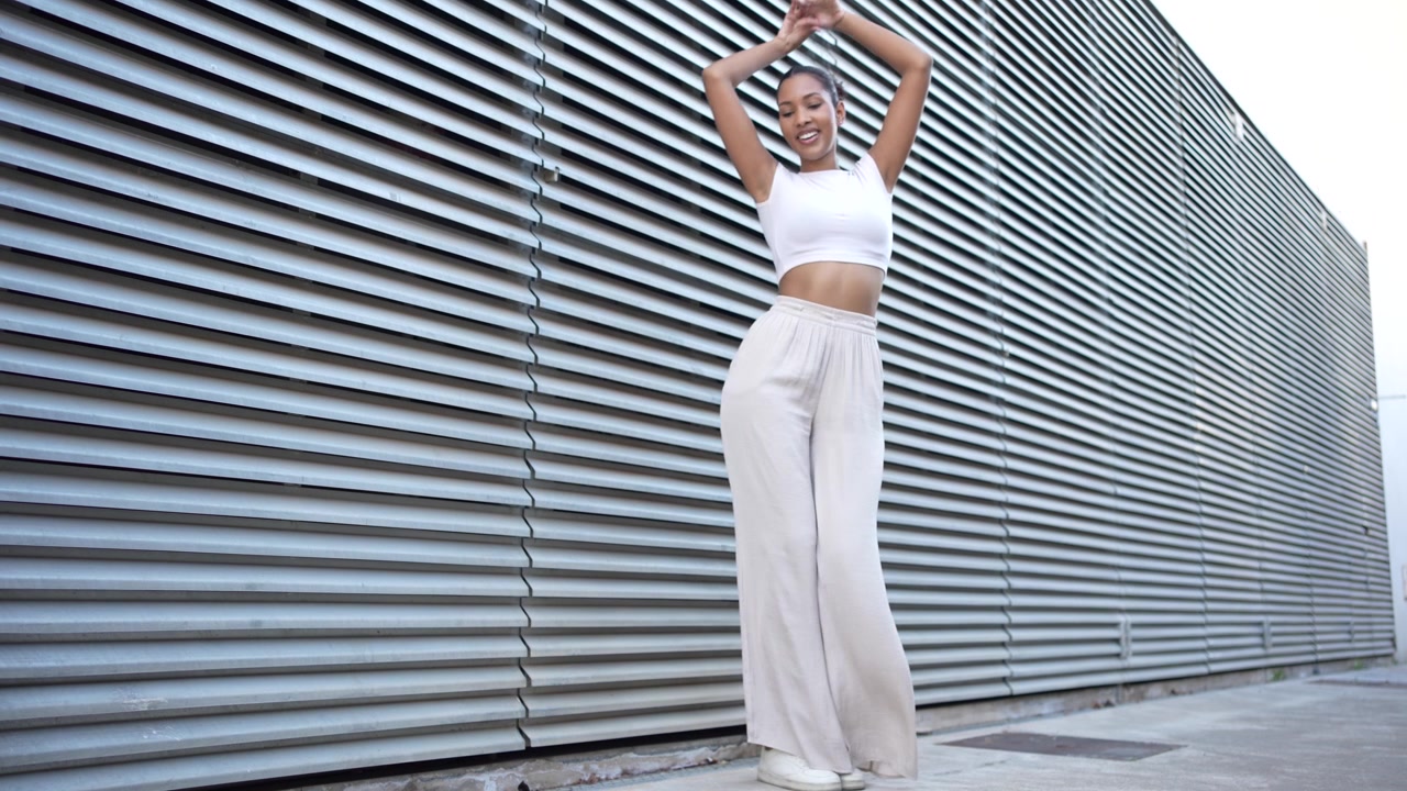 Una joven elegante posando con confianza con un atuendo casual chic contra un fondo urbano.