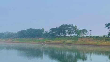 Wide-shot-of-traditional-Bangladeshi-boat-with-fisherman,-Surma-river-navigation