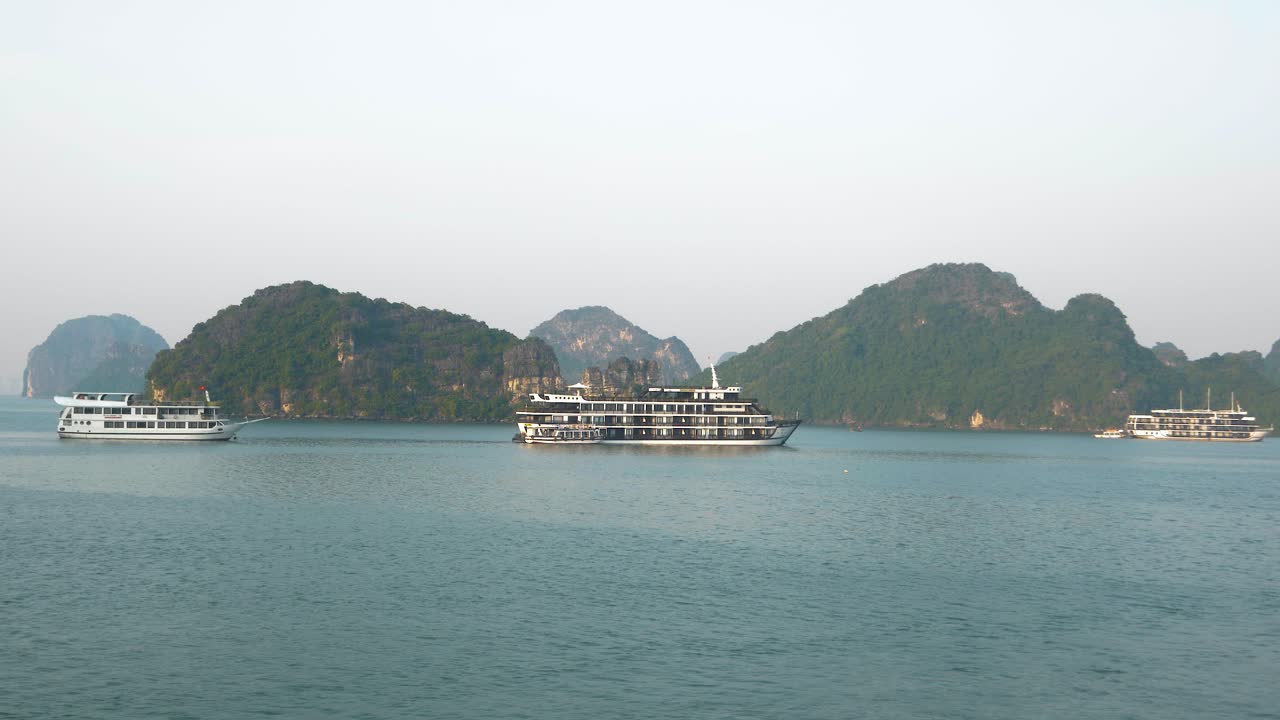 Ha Long Bay's Evening Glow: Cruise Boats Surrounded by Rocky Limestone Mountains