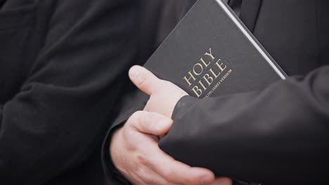 bible, funeral and hands closeup of a priest