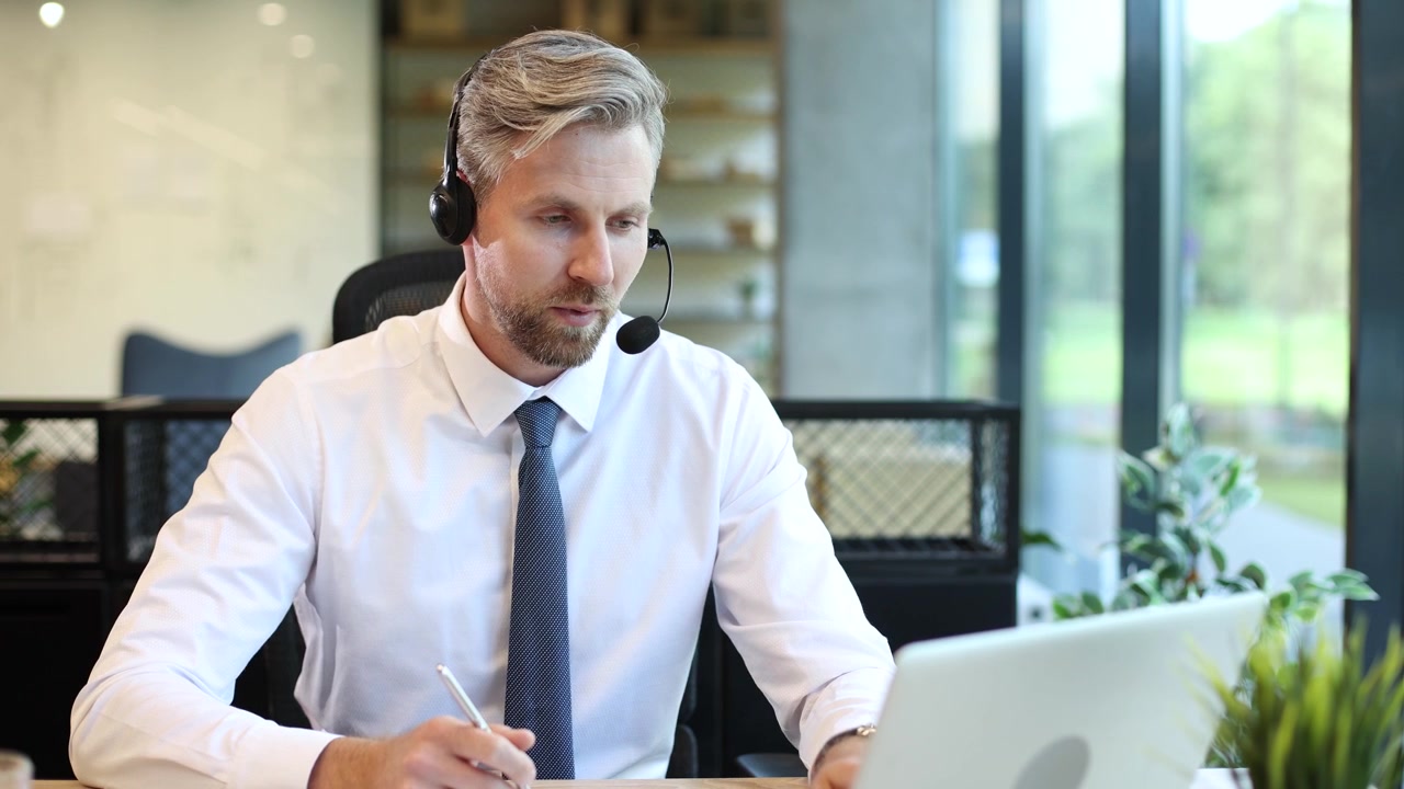 Kundeservicemedarbejder, der arbejder på bærbar computer med headset