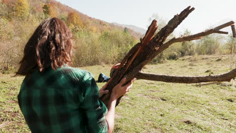 follow shot of young woman with wood for camp fire