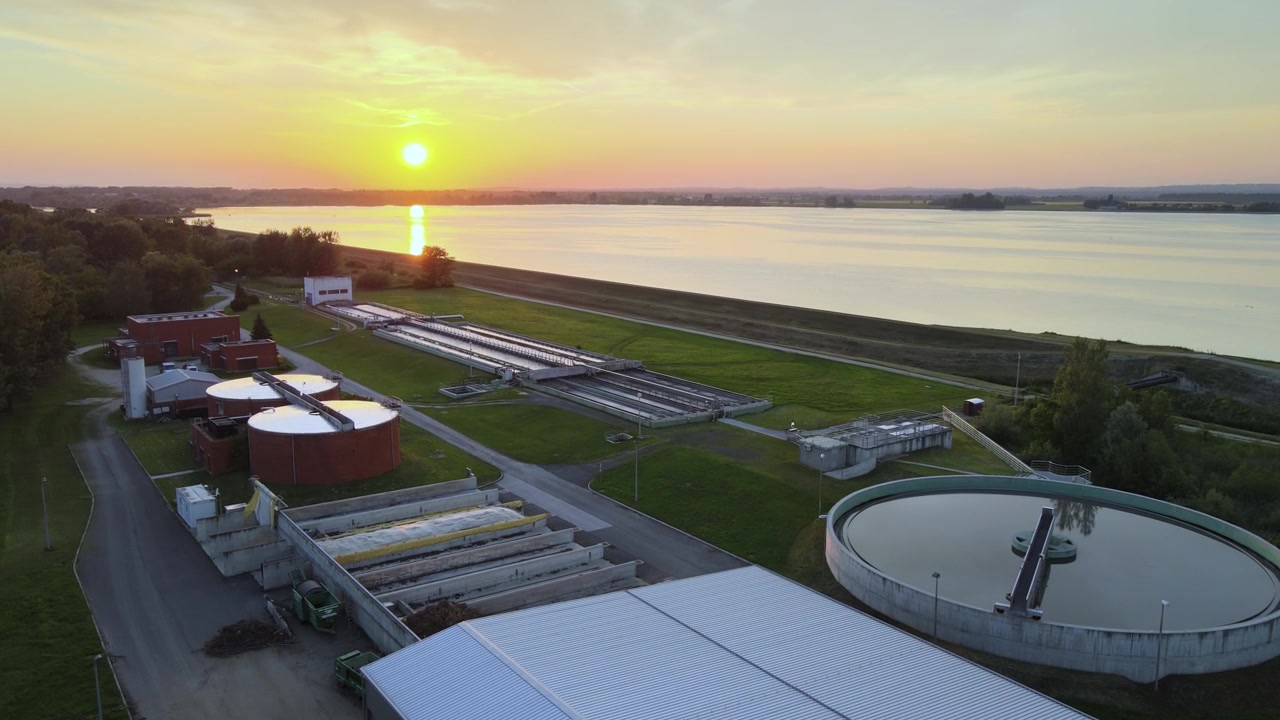 Drone aerial of a municipal wastewater treatment plant with clarifiers and processing tanks at sunset. Environmental infrastructure supporting water purification, sanitation sustainable resources