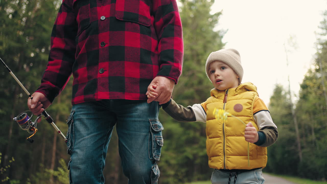 el abuelo y el niño están caminando en la naturaleza en la mañana de fin de semana yendo a pescar niño y viejo pescador