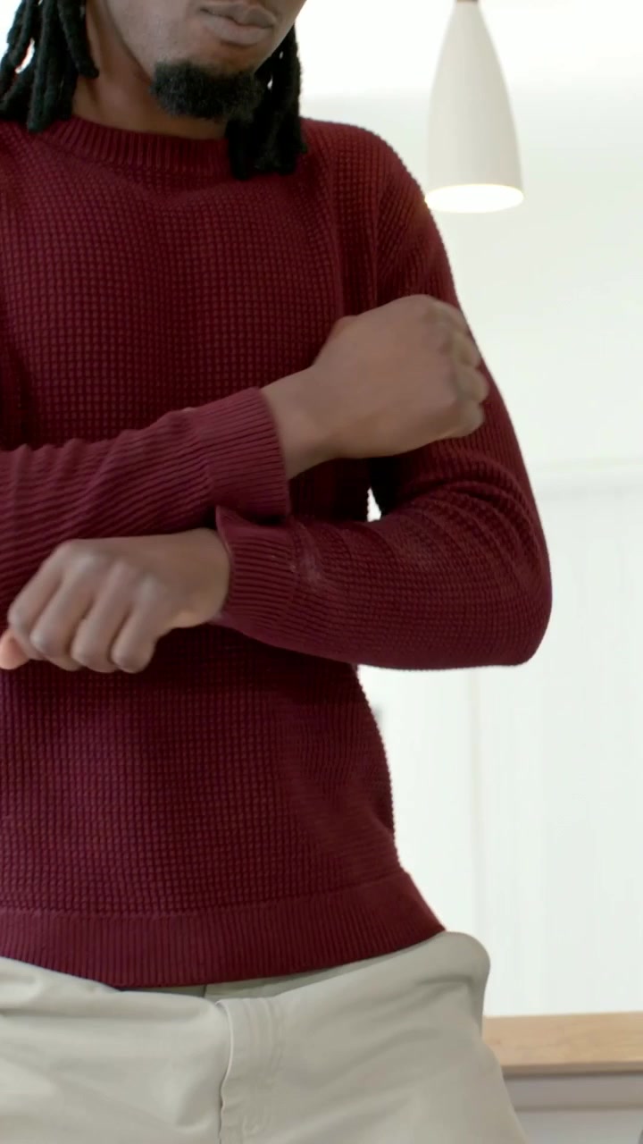 Video verticale: Uomo che balla, inizia con le braccia incrociate, si esercita in cucina con un maglione bordeaux chiaro.