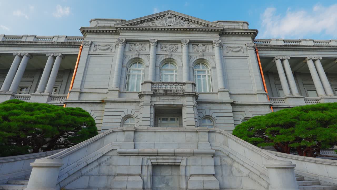 An imposing low-angle shot of the majestic stone central staircase and neoclassical main facade of the Akasaka Palace in Tokyo, Japan