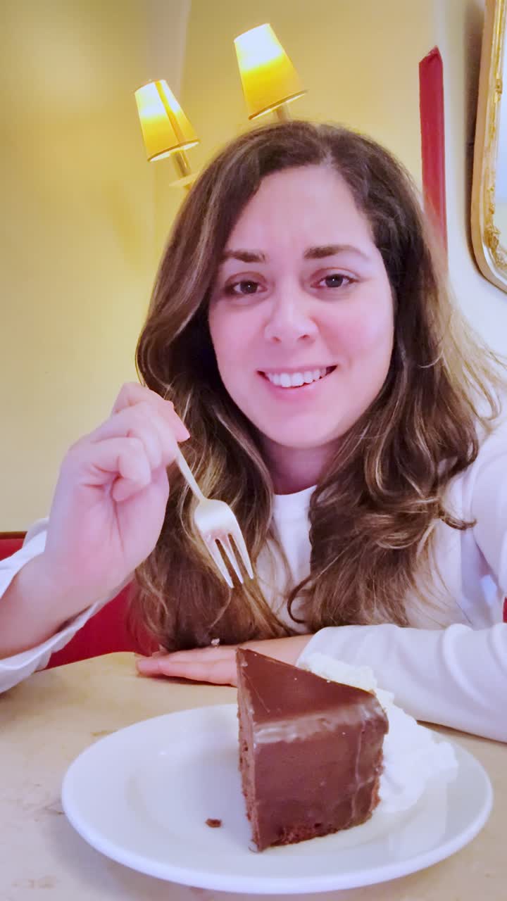 Mujer feliz disfrutando de una porción de pastel de chocolate en una cafetería