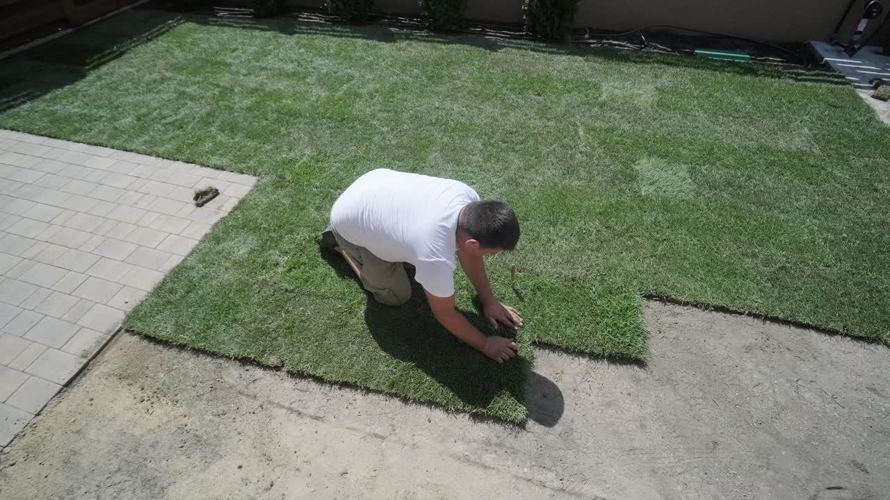 jardinero colocando césped en el patio privado con valla de madera