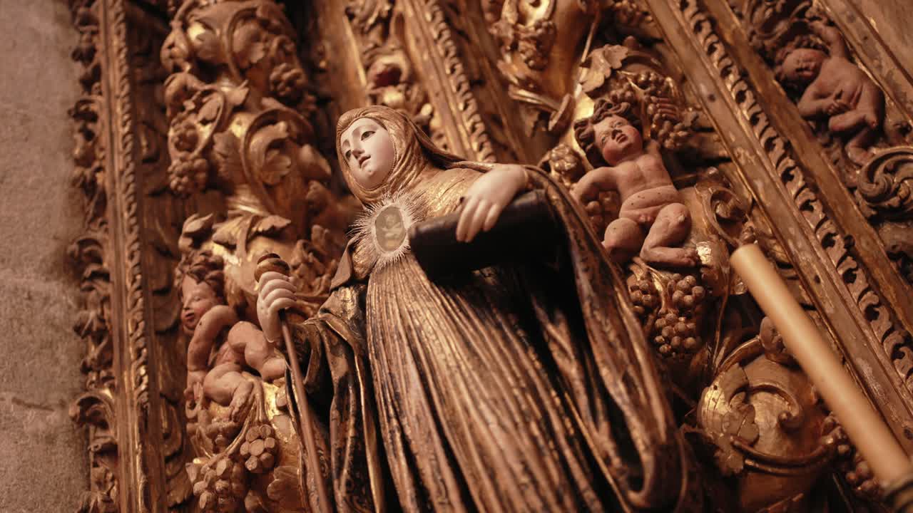 Low angle close up of a gilded religious statue holding a monstrance and book in ornate altar