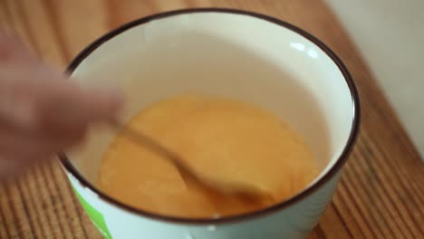 a close up shot of a chef mixing raw eggs in a white bowl, brown wooden plate, making breakfast 4k video