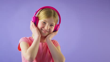 studio shot of girl wearing wireless headphones listening to music against yellow studio background - shot in slow motion