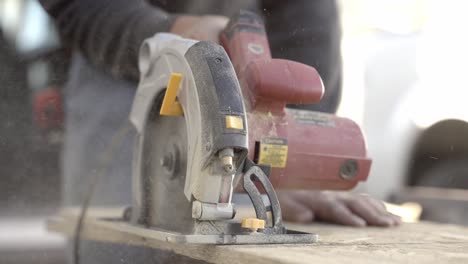 close up shot of red color circular saw cutting wood with sawdust flying