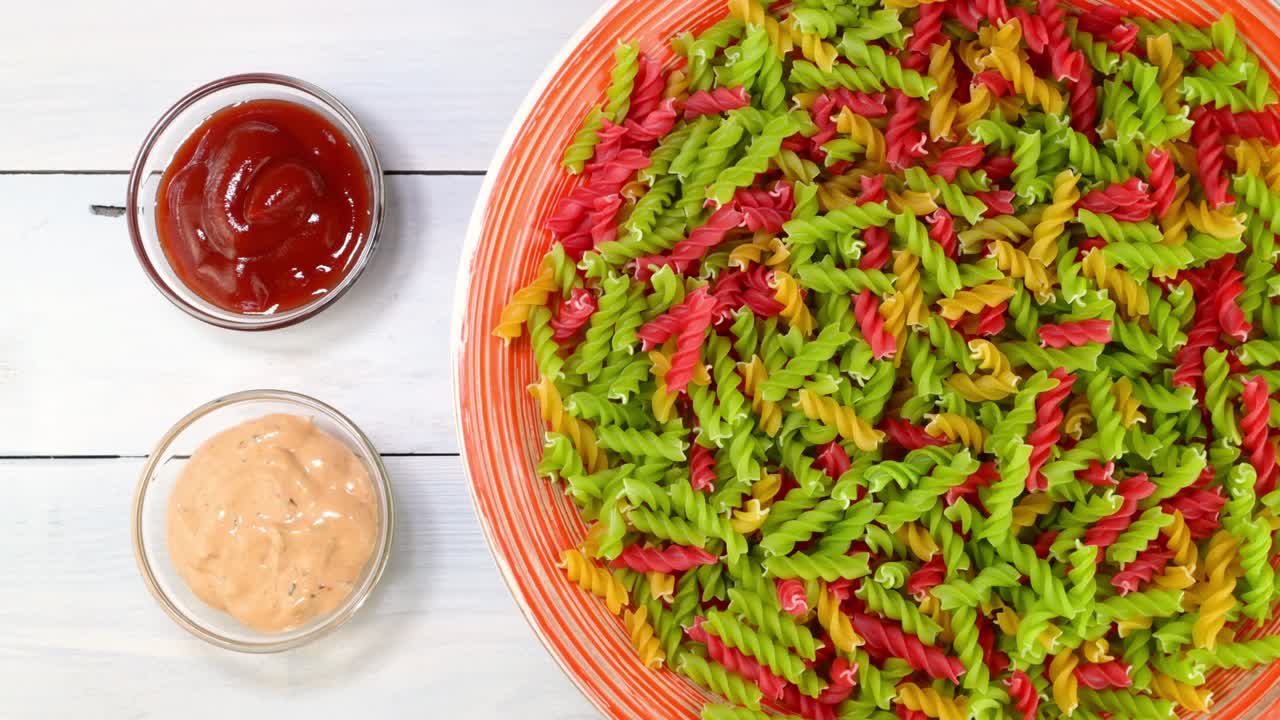 다채로운 익히지 않은 원시 이탈리아 푸실리 파스타가 접시에서 회전 테이블에서 천천히 회전합니다.