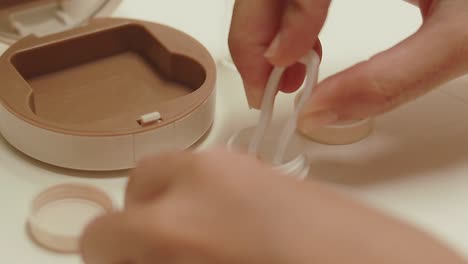 picking up a brown contact lens using tweezers to promote hygiene in a self-care and eye care routine