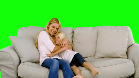 daughter jumping in the arms of her mother in the sofa on green screen