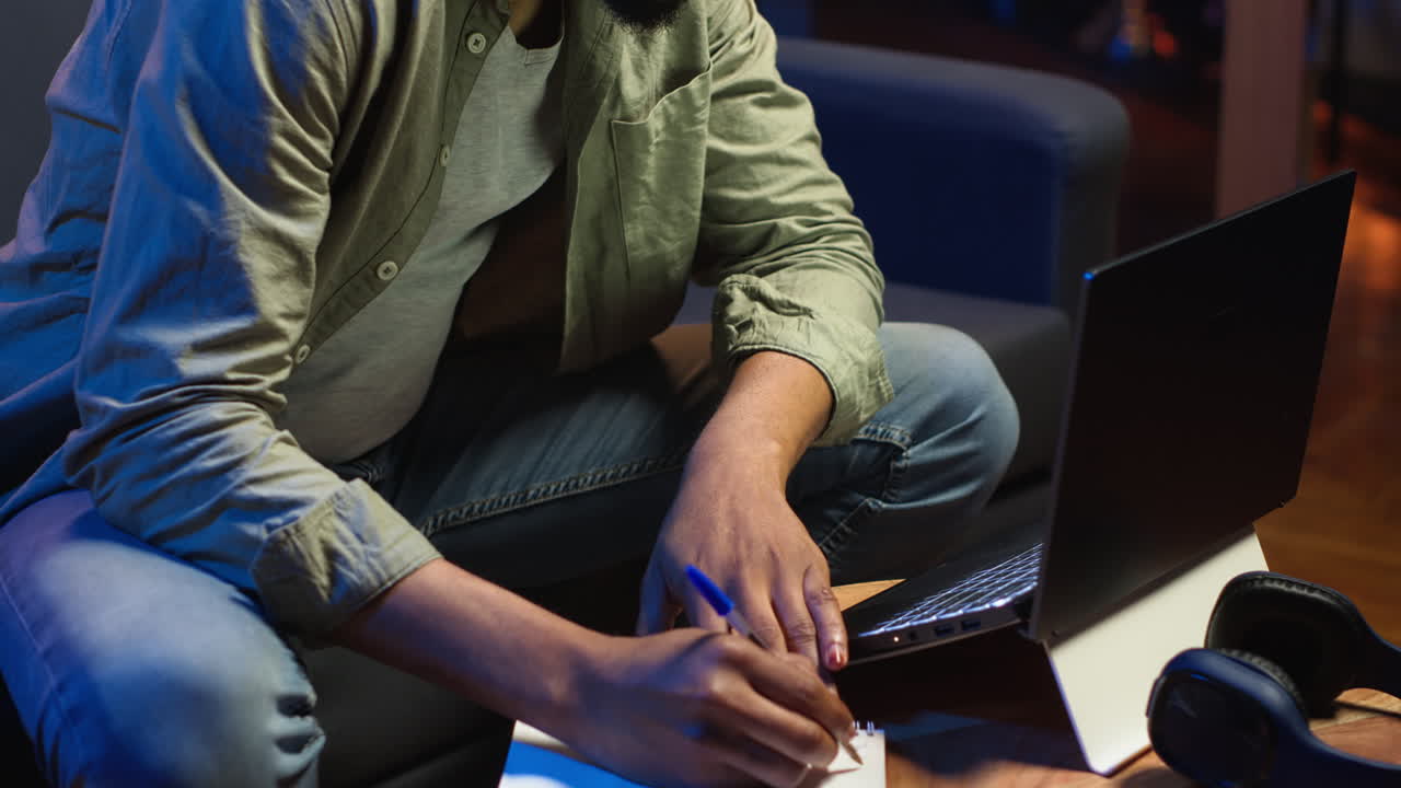 Vertical Video Black freelancer taking notes on his textbook in order to solve his tasks