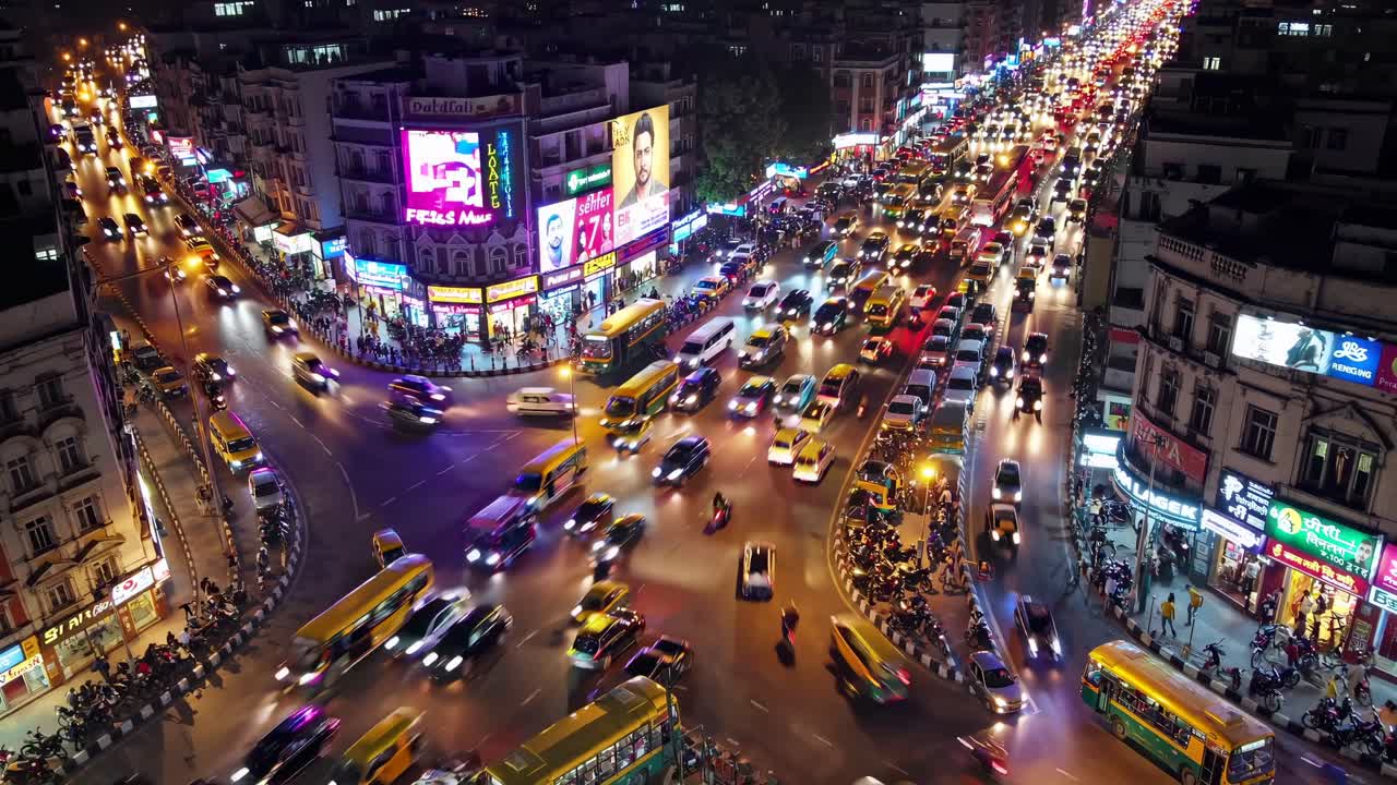 Aerial view of a bustling city intersection at night, showcasing vibrant lights and heavy traffic