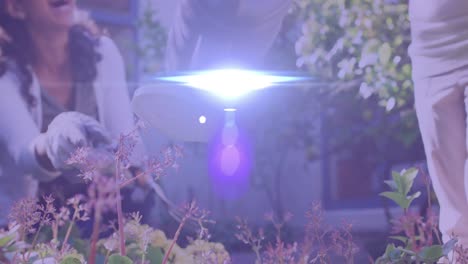 spot of light moving against mid section of a caucasian girl watering plants in the garden