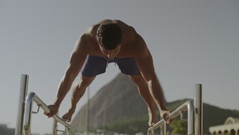 man doing calisthenics exercises on parallel bars outdoors
