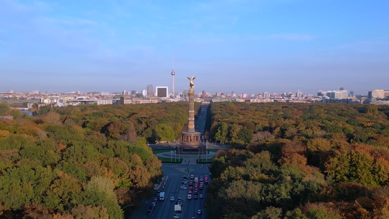 iconic landmark surrounded by colorful autumn foliage, with the cityscape in the background under a clear blue sky. Dramatic aerial view flight drone shot footage from above