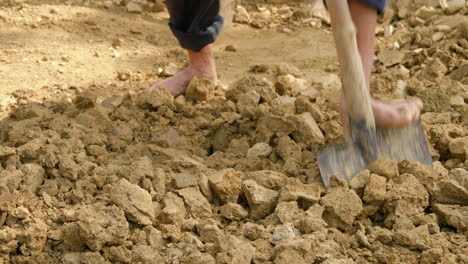 A-barefoot-man-collects-new-clay-soil,-the-raw-material-for-traditional-Asian-pottery,-in-a-rural-setting,-showcasing-the-craft-and-tradition-of-pottery-making