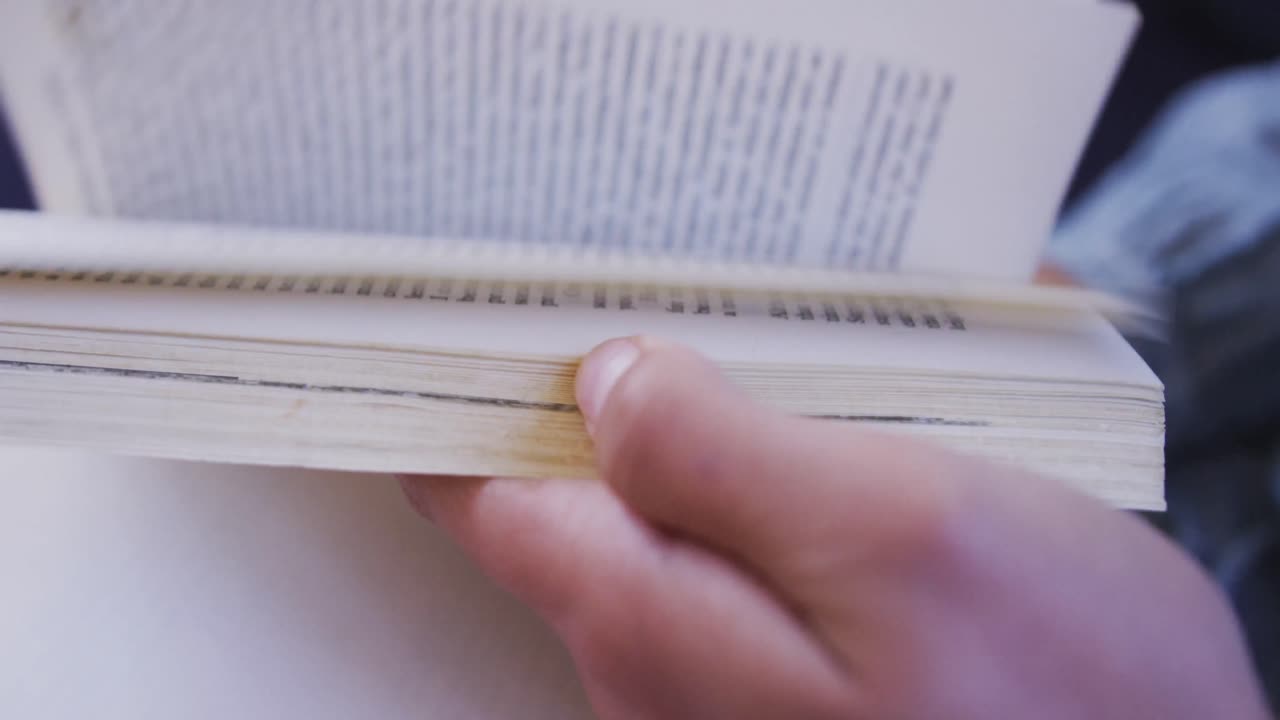 estudiante asiática vestida con un hijab azul acostada en el suelo y leyendo un libro