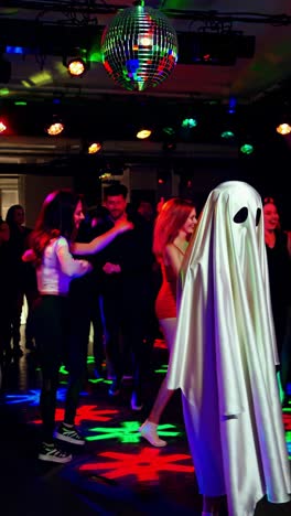 people dancing at a party with a ghost costume and colorful disco lights