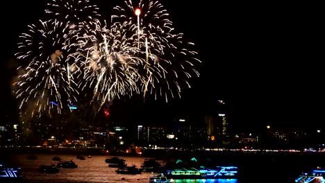 4k footage of real fireworks festival in the sky for celebration at night with city view at background and boat floating on the sea at foreground at coast side