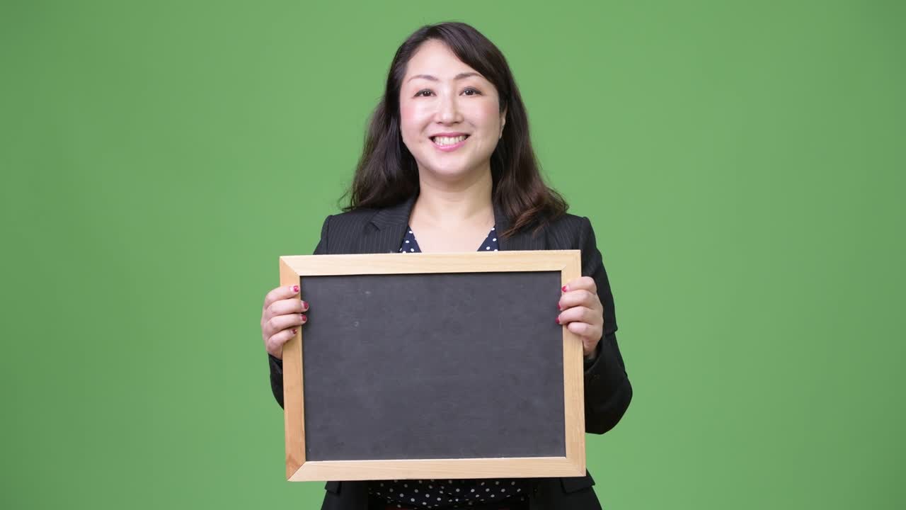 성숙하고 아름다운 아시아 사업가 여성이 블랙보드를 보여주고 있습니다.