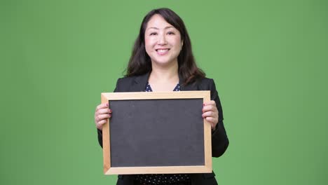성숙하고 아름다운 아시아 사업가 여성이 블랙보드를 보여주고 있습니다.