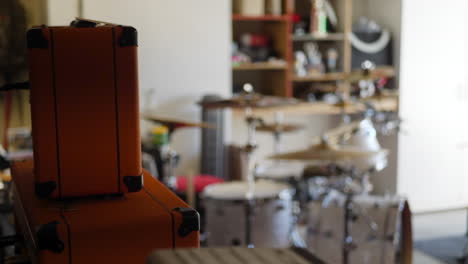 un baterista se levanta de su instrumento durante una práctica de banda de rock and roll en un garaje con amplificador de guitarra y batería.
