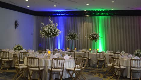 sala de reuniones colorida y elegante en un hotel, decorada para una celebración de recepción de boda, mesas redondas con piezas centrales altas con flores de gypsophila paniculata y rosas blancas