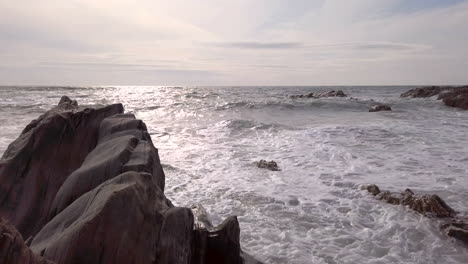 waves breaking against a rocky cove on a summer’s evening