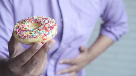 persona que sostiene una rosquilla con dolor de estómago