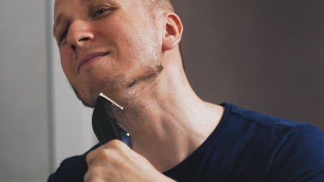 Un-Hombre-Alegre-Se-Afeita-La-Barba-Con-Una-Navaja-Mirando-En-Un-Espejo-Grande