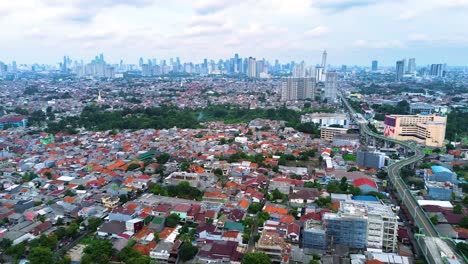 vista aérea de la expansión suburbana de yakarta, mostrando densos techos residenciales con rascacielos del centro de yakarta en el fondo en un día nublado.