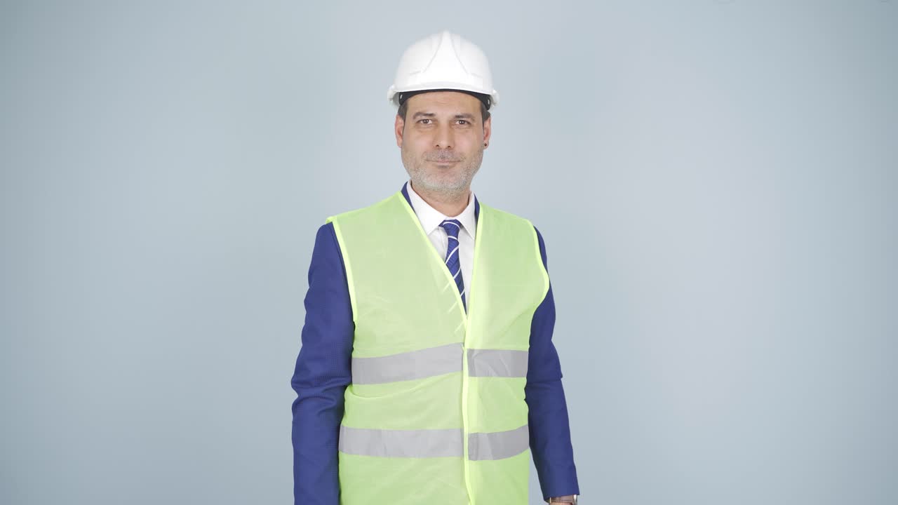 el ingeniero mira a la cámara y hace una señal de alto.