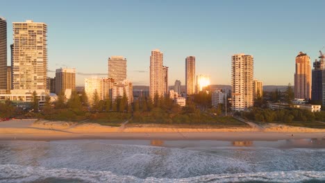 aerial view of gold coast's skyline and beach at sunrise, capturing vibrant reflections and serene ocean waves